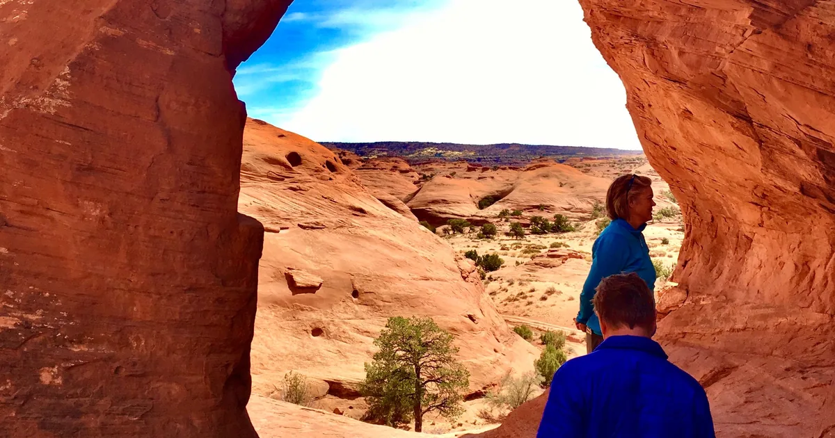 Visitors walking through a sandstone arch in the backcountry of Monument Valley